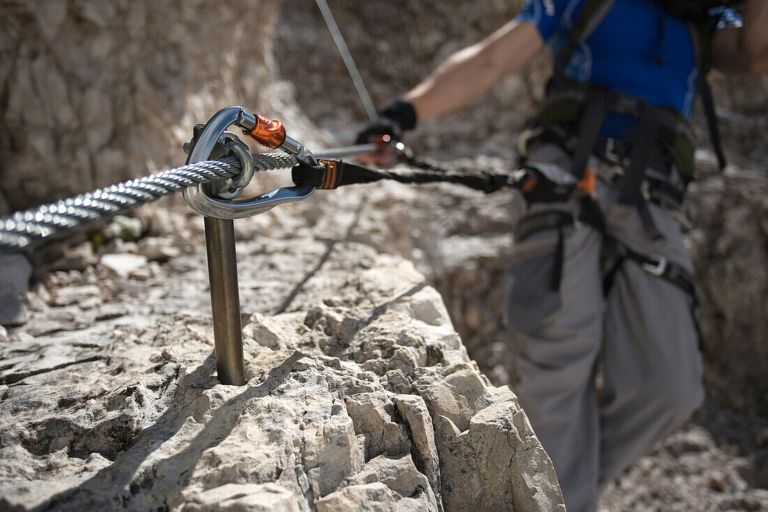 Caucasian climber hooked to stakes on mountain slope