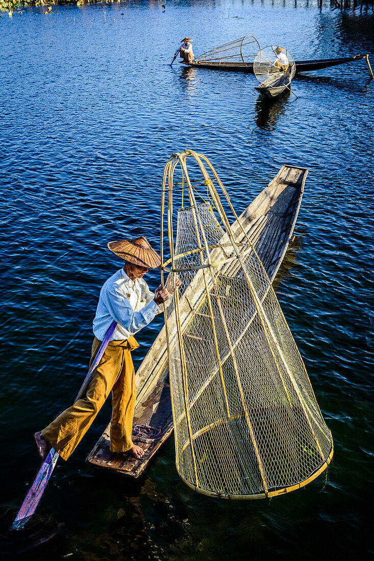 Asian fisherman fishing in canoe on river