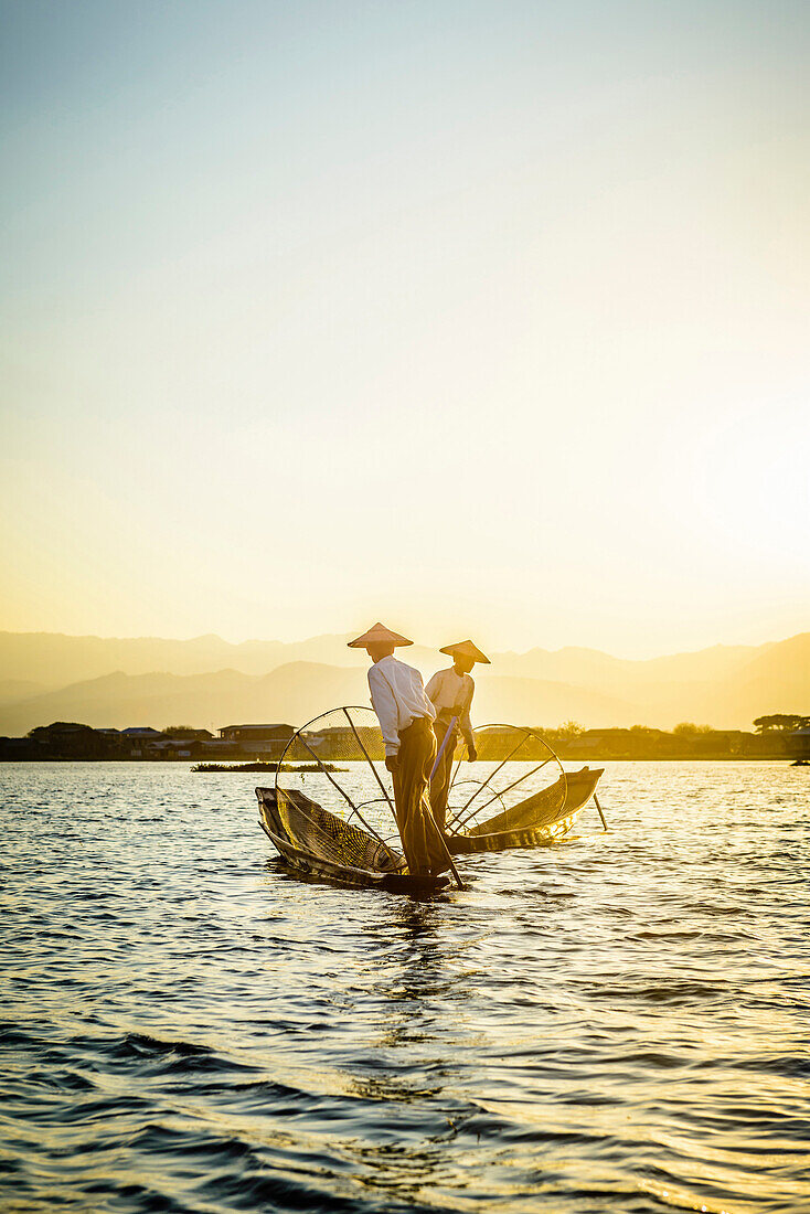 Asian fishermen fishing in canoes on river