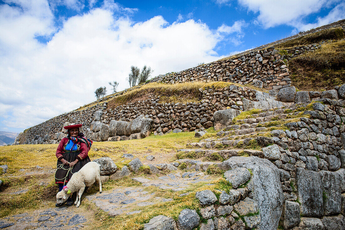 Older Hispanic woman walking llama on stone steps