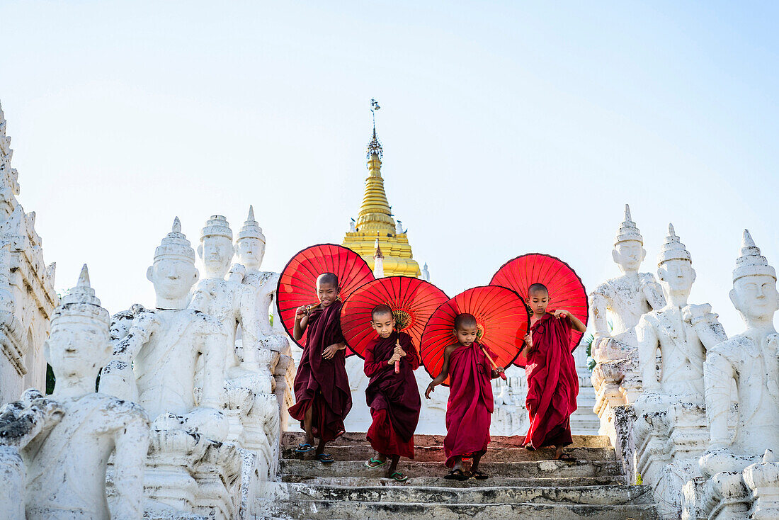 Asian children with parasols balancing on Buddhist shrine