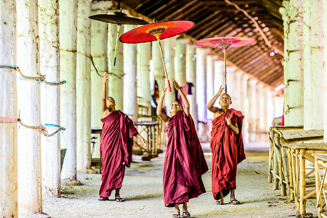 Asian monks-in-training playing with parasols in hallway