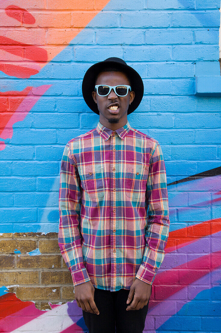 Black man wearing sunglasses near colorful wall