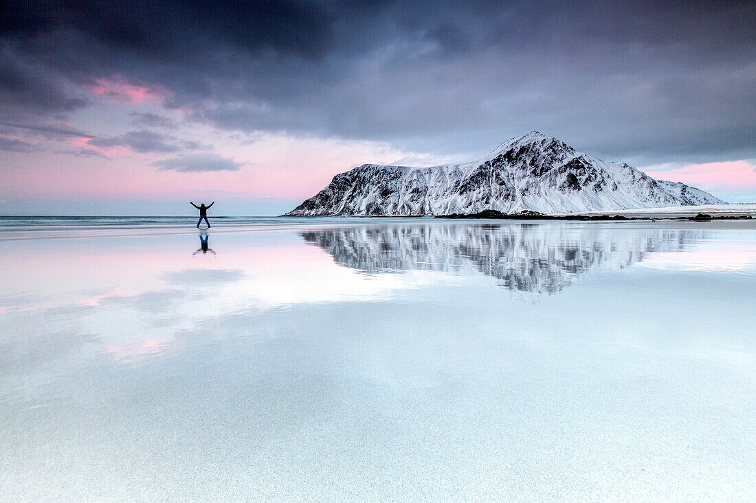 Sunset and hiker on Skagsanden beach surrounded by snow covered mountains, Flakstad, Lofoten Islands, Arctic, Norway, Scandinavia, Europe