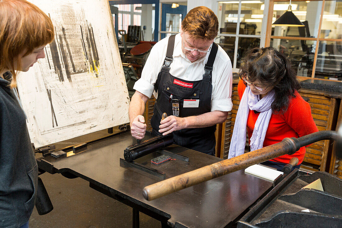 Visitor and worker printing using a print roller, Museum of Printing Arts Leipzig, Leipzig, Saxony, Germany