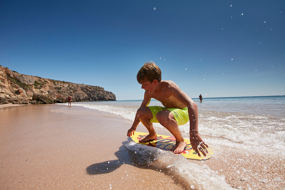 Young skimboarder on Zavial beach, West Coast, Algarve, Portugal