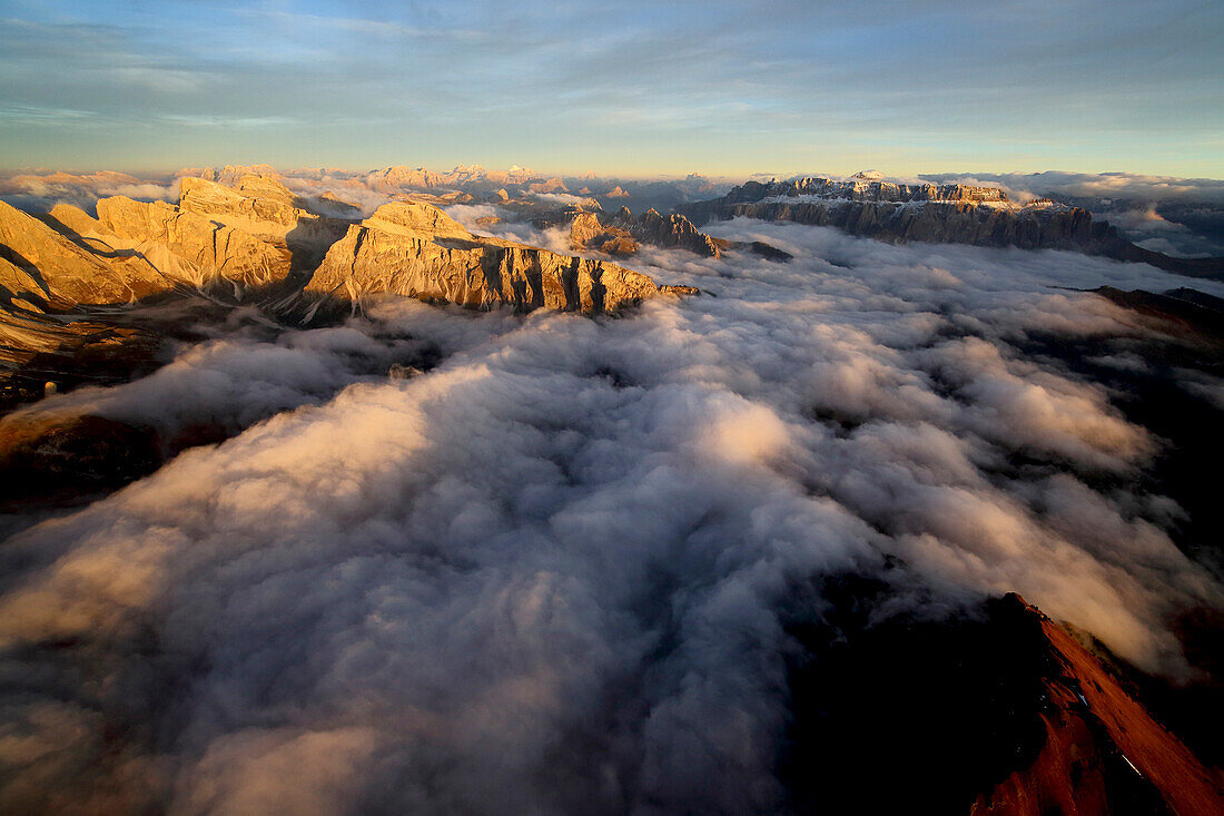 Aerial shot of Sella Group Alps surrounded by clouds at sunset in the Dolomites, Val Funes, Trentino-Alto Adige South Tyrol, Italy, Europe