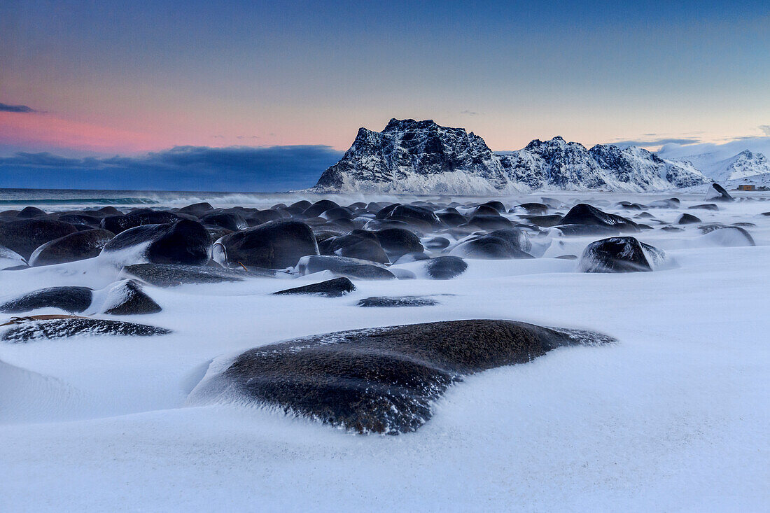 The cold wind that blows constantly shapes the snow on the rocks around Uttakleiv at dawn, Lofoten Islands, Arctic, Norway, Scandinavia, Europe