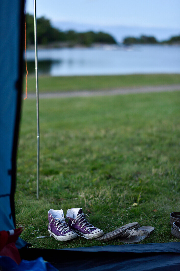 Blick aus dem Zelt auf den See mit Mädchen Schuhen im Vordergrund, Campingplatz, Västervik, Smaland, Schweden