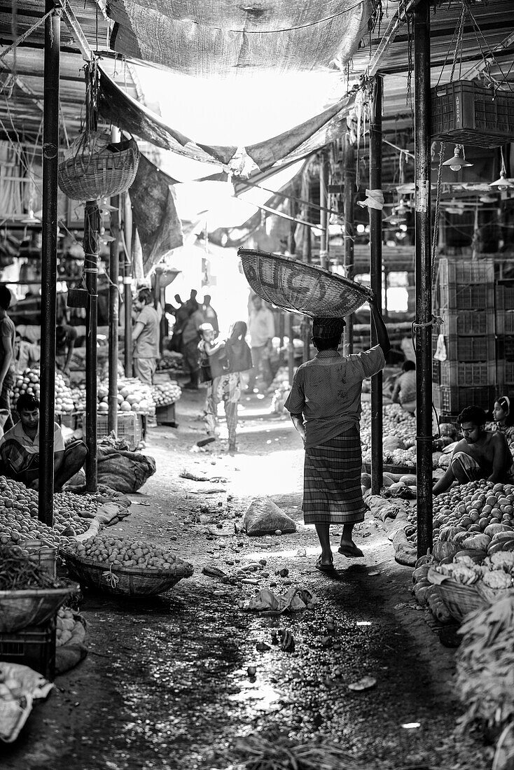 Man carrying basket on his head at a local market, Dhaka, Bangladesh