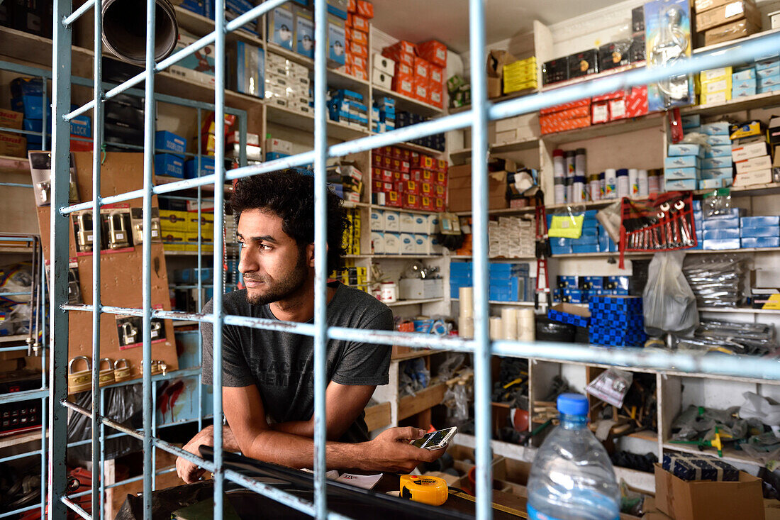 Man behind barred hardware stall, Kigamboni, Tanzania, Africa