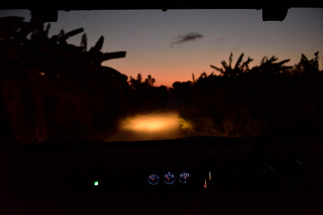 Blick durch die Windschutzscheibe eines Autos bei nächtlicher Buschfahrt in Kigamboni, Tansania, Afrika