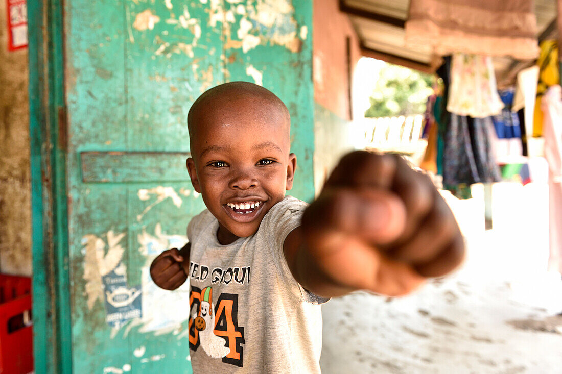 lachender Junge mit geballter Faust, Kigamboni, Tansania, Afrika