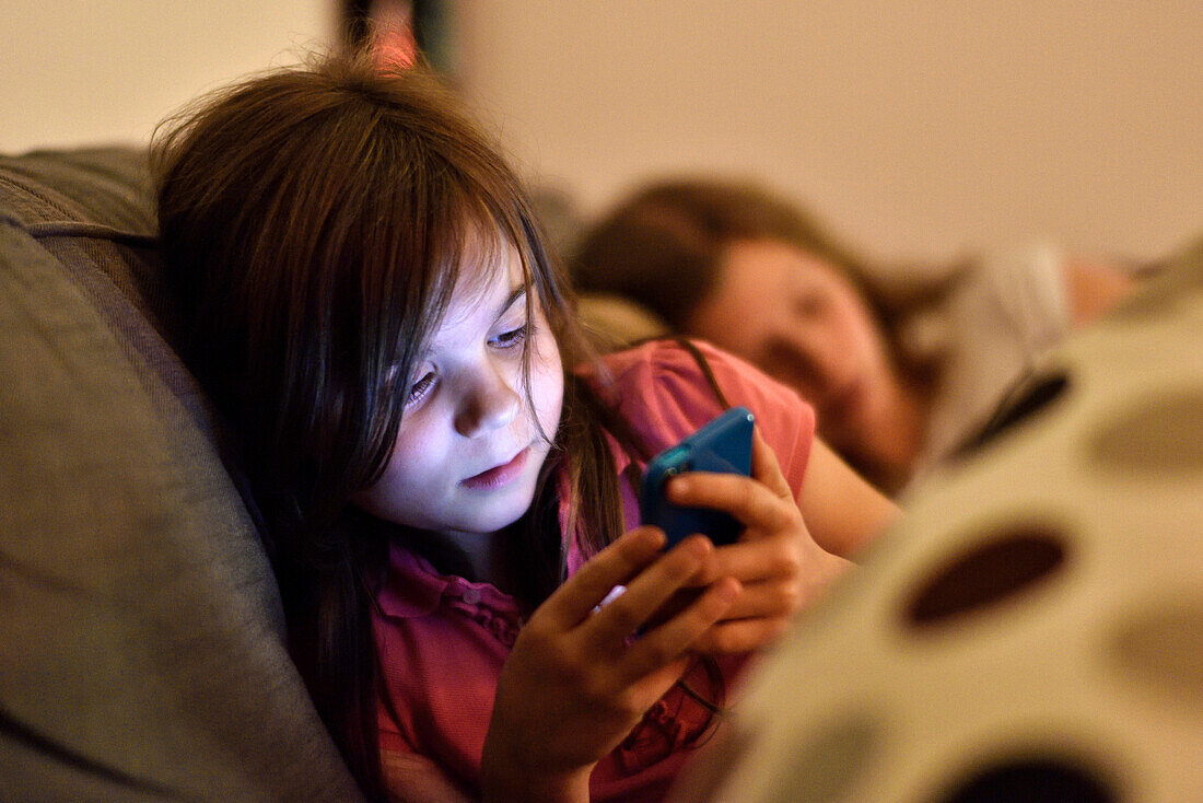 Young girl with smartphone on the sofa, Hamburg, Germany, Europe