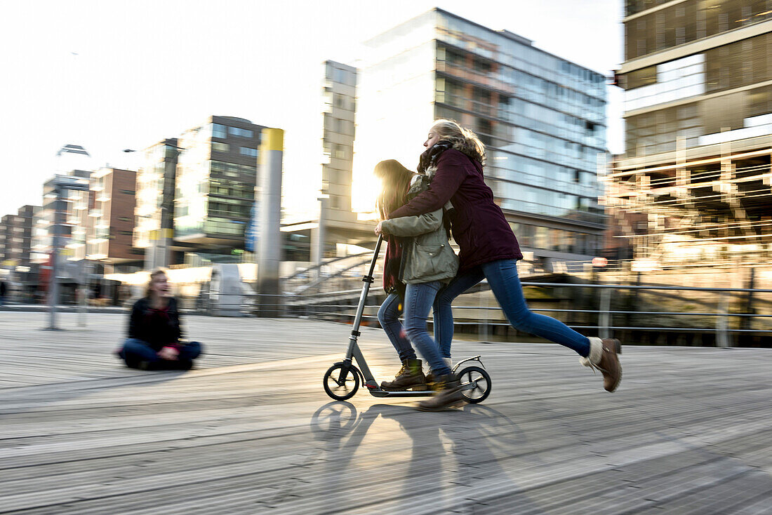 2 girls on a scooter in Hafencity, Hamburg, Germany, Europe