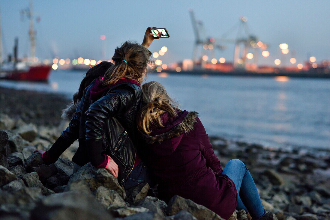 3 girls making selfie pictures at the Elbe River beach, Oevelgoenne, Hamburg, Germany, Europe