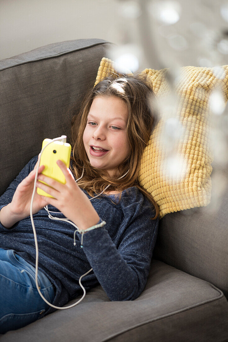 Girl listening to music at home on her smartphone, Hamburg, Germany, Europe
