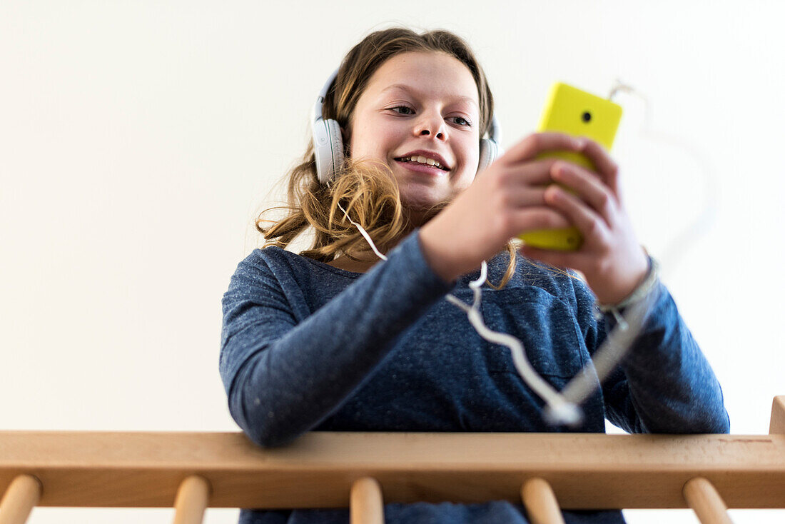 Girl listening to music at home on her smartphone, Hamburg, Germany, Europe