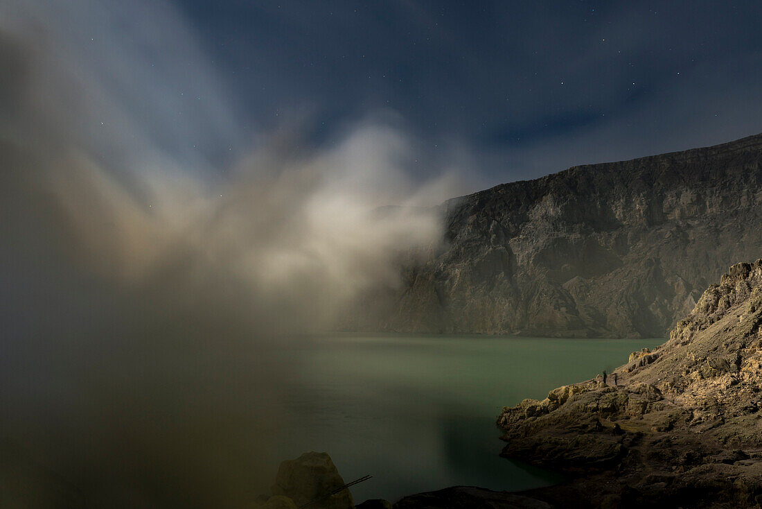 Blue acid lake with sulfur gases of the active volcano Ijen at night. Full moon illuminates the lake and the surrounding area, East Java, Ijen volcano, Indonesia