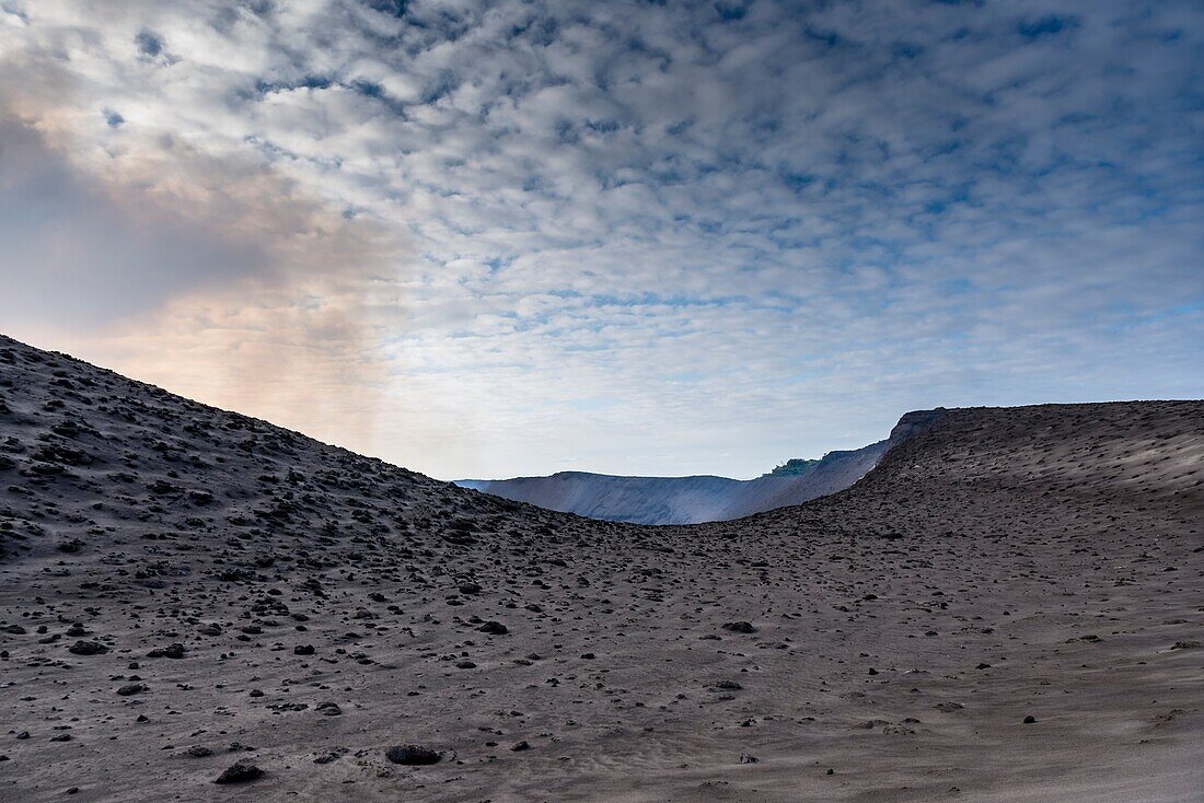 Ash field shortly before the crater of the active volcano Yasur with emitting gases. Blue, slightly overcast skies. - Vanuatu, Ambrym Island, South Pacific