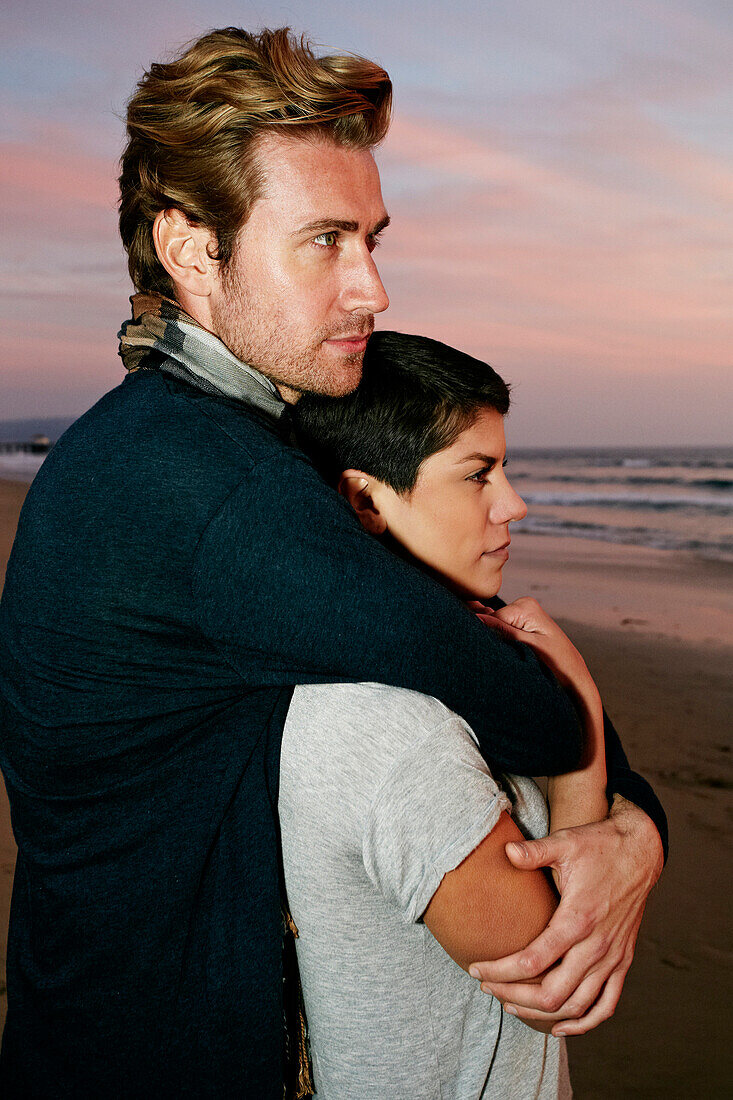 Couple hugging on beach at sunset