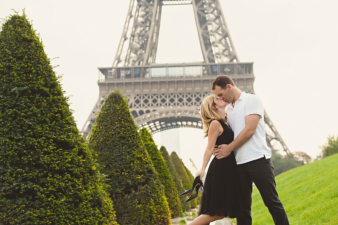 Caucasian couple kissing near Eiffel Tower, Paris, Ile-de-France, France