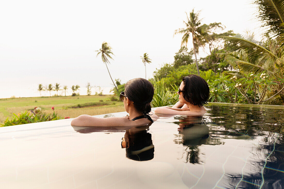 Women admiring scenic view in infinity pool