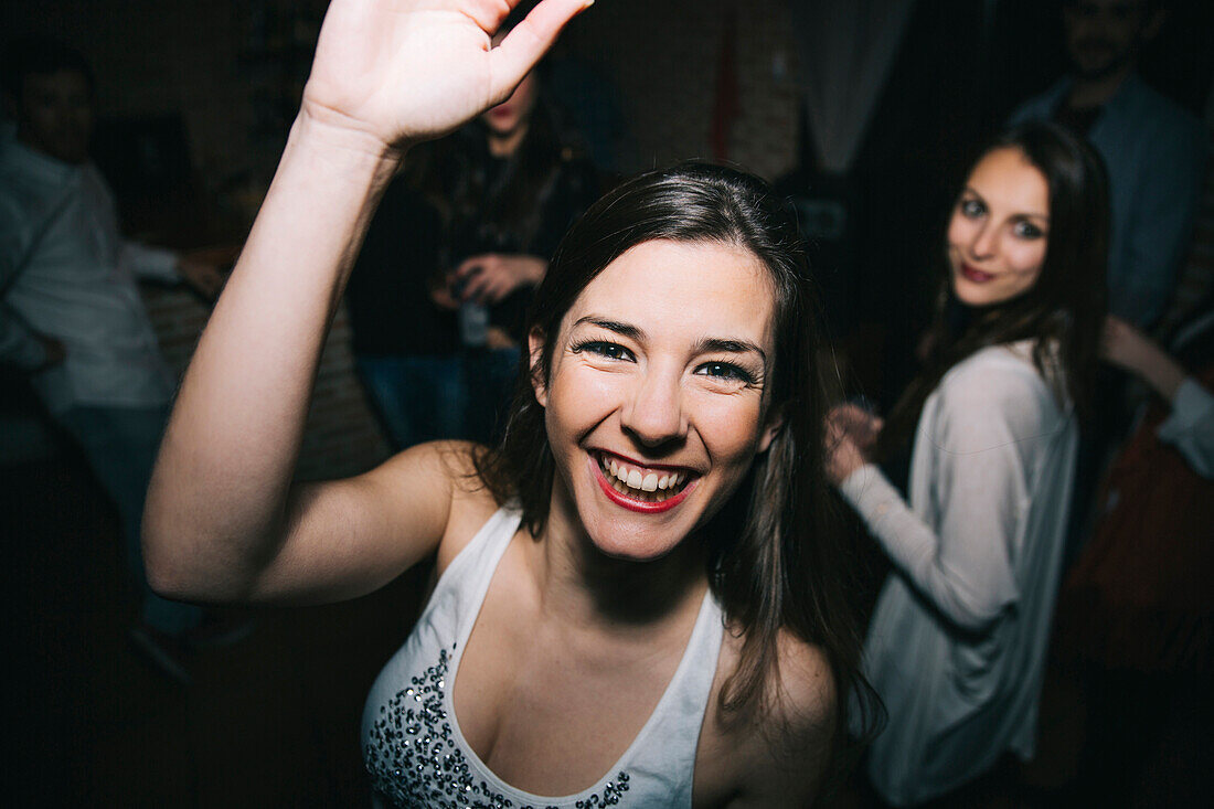 Smiling woman waving in nightclub