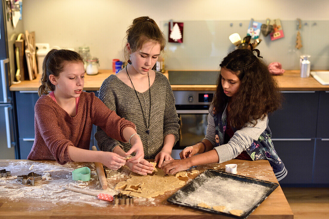 11 years old girls baking christmas cookies, cutting out dough, Hamburg, Germany