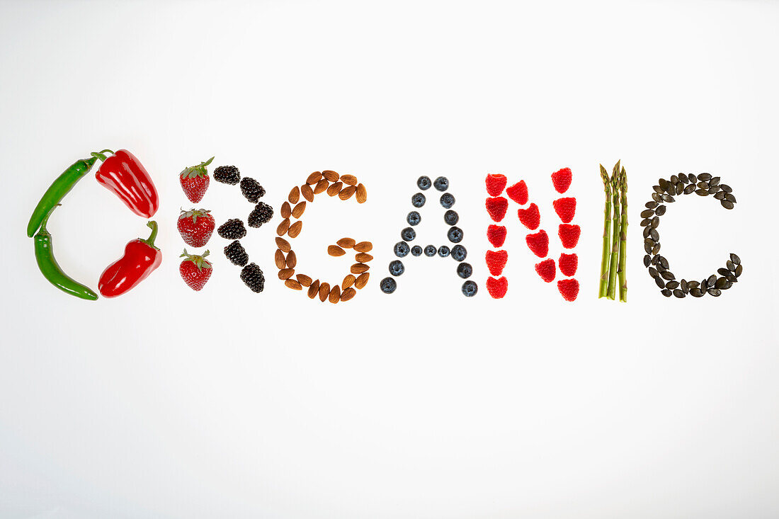 The word Organic spelled from peppers, strawberries, blackberries, almonds, blueberries, raspberries, asparagus, and pumpkin seeds on a white background, Calgary, Alberta, Canada
