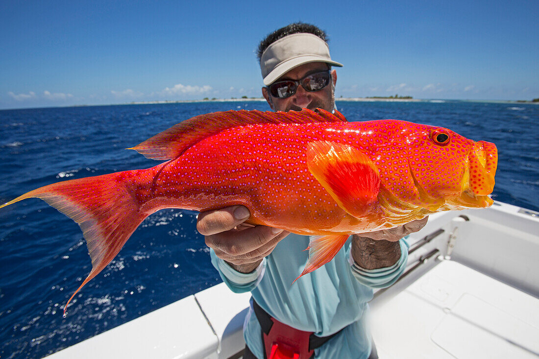 Fisherman holding a fresh caught red and orange fish, Tahiti