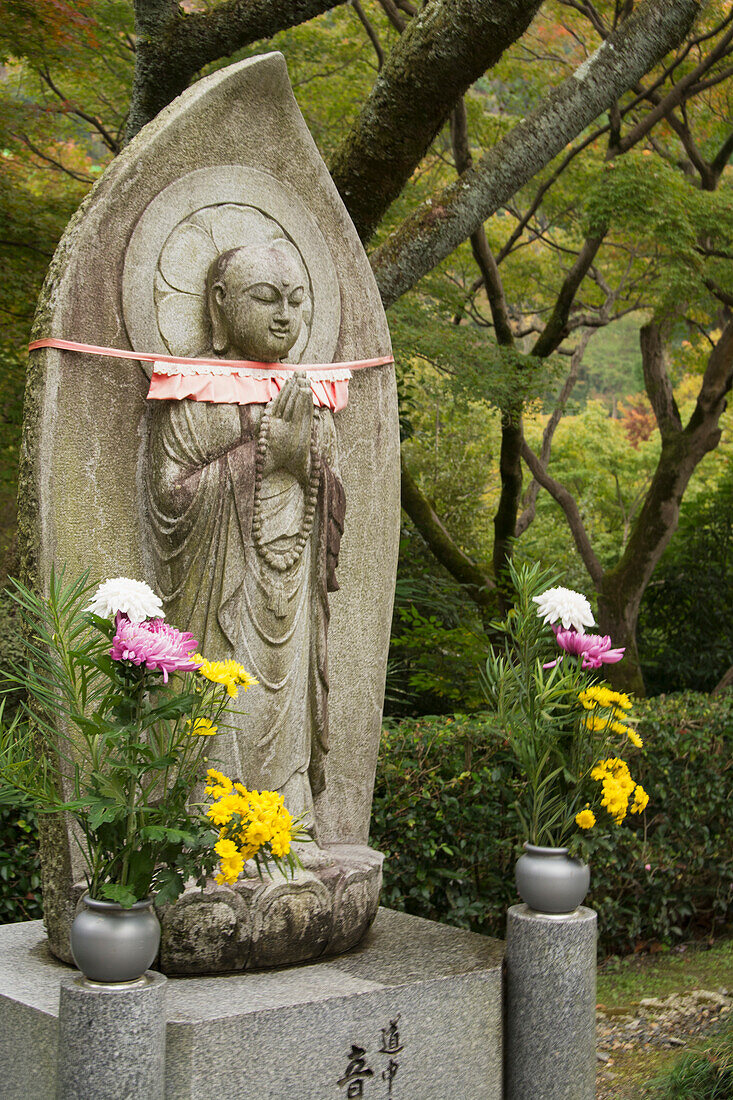 Statue of a standing Buddha and flowers, Kyoto, Japan
