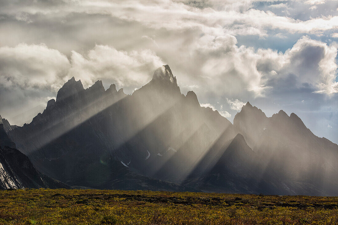 Sunlight streaks through rain and mist by Tombstone Mountain in Tombstone Territorial Park, Yukon, Canada