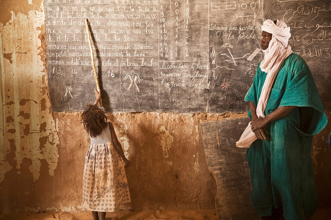 Tuareg teacher and girl in front of a blackboard at a primary school in Tiriken, Mali