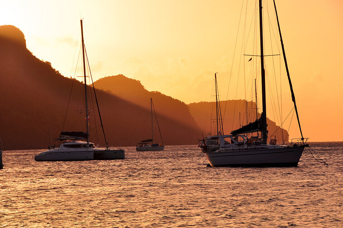 Segelschiffe bei Sonnenuntergang vor Insel, Meer, Bequia, St. Vincent und die Grenadinen, Saint Vincent and the Grenadines, Kleine Antillen, Westindische Inseln, Windward Islands, Antillen, Karibik, Mittelamerika