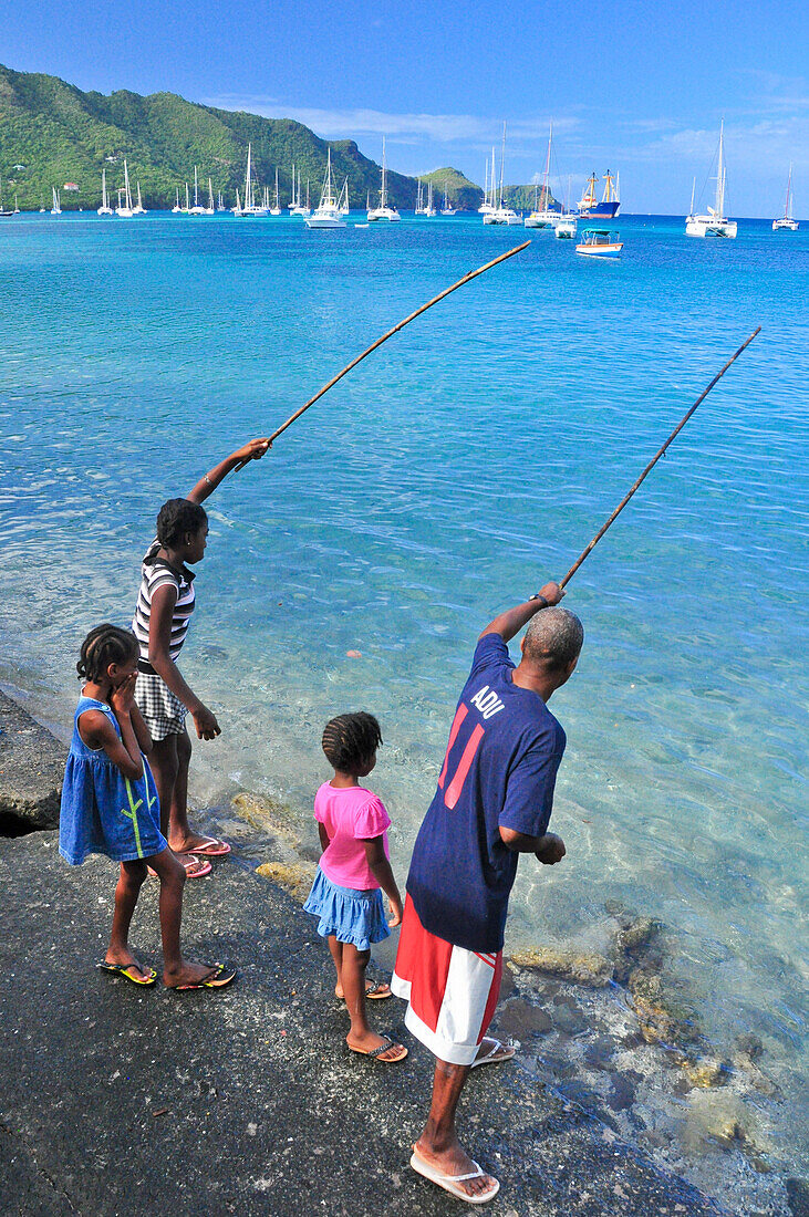 Mann und Kinder angeln am Strand, Port Elizabeth, Insel Bequia, St. Vincent und die Grenadinen, Saint Vincent and the Grenadines, Kleine Antillen, Westindische Inseln, Windward Islands, Antillen, Karibik, Mittelamerika