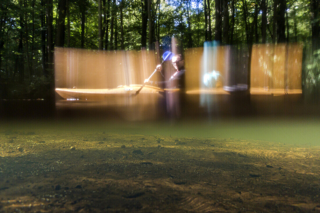 Kayak tourist paddling through the Spreewald biosphere reserve. Photograph taken at the level of the water surface. Half above and half below the water surface, biosphere reserve, Schlepzig, Brandenburg, Germany