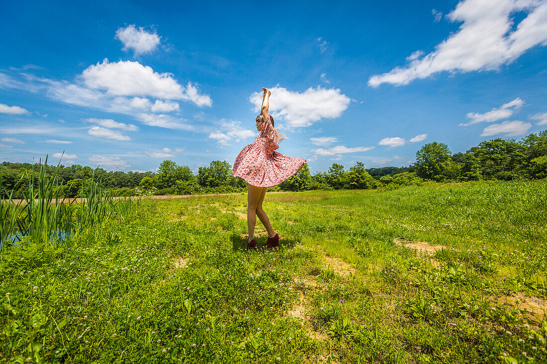 Young Adult Woman in Pink Dress Dancing in Field