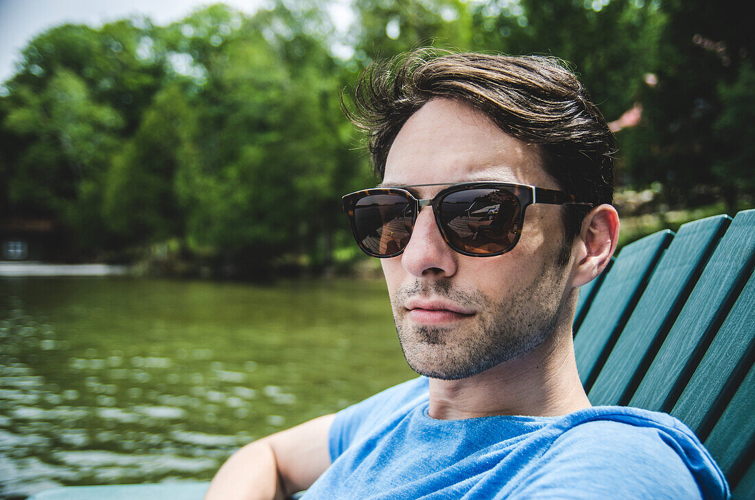 Young Adult Man in Sunglasses Looking Serious by Lake