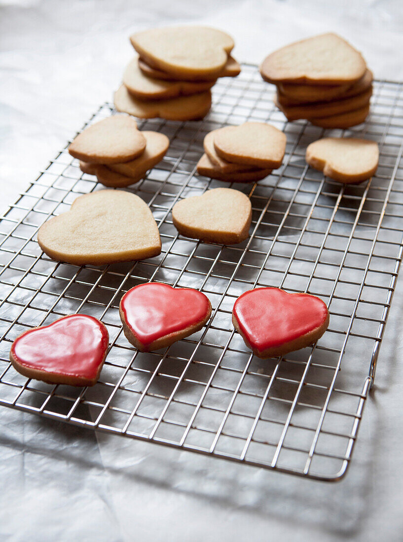 Small and Large Heart-Shaped Shortbread Cookies on Cooling Rack, Some with Red Glaze