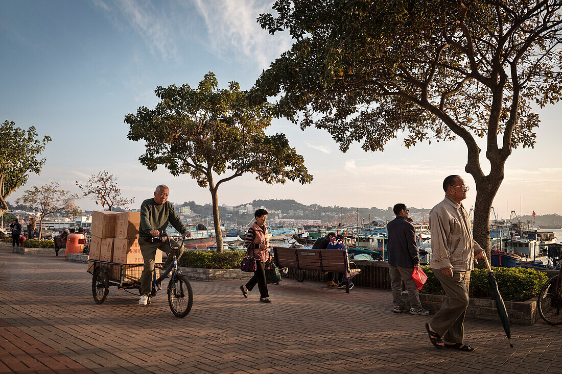 alter chinesicher Mann auf Dreirad transportiert Waren durch die Küstenstraße von Insel Cheng Chau, Hongkong, China, Asien