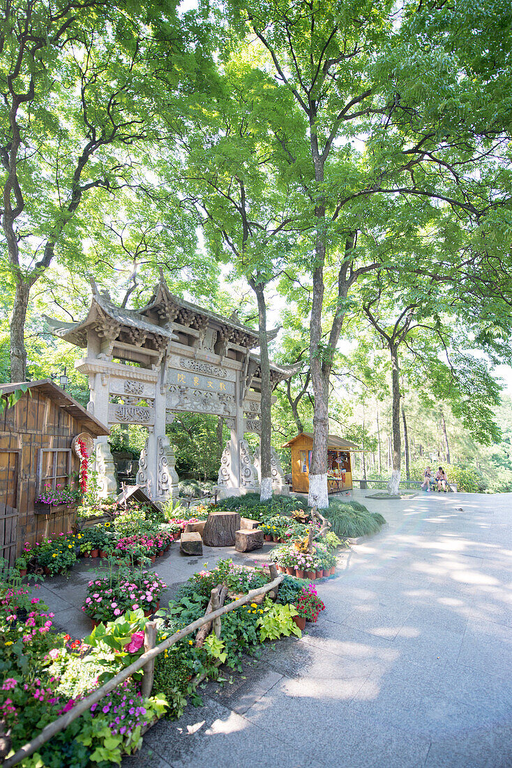 Traditional Chinese stone gate, lush surroundings and floral decorations at Wansong Academy, Hangzhou, Zhejiang, China, Asia