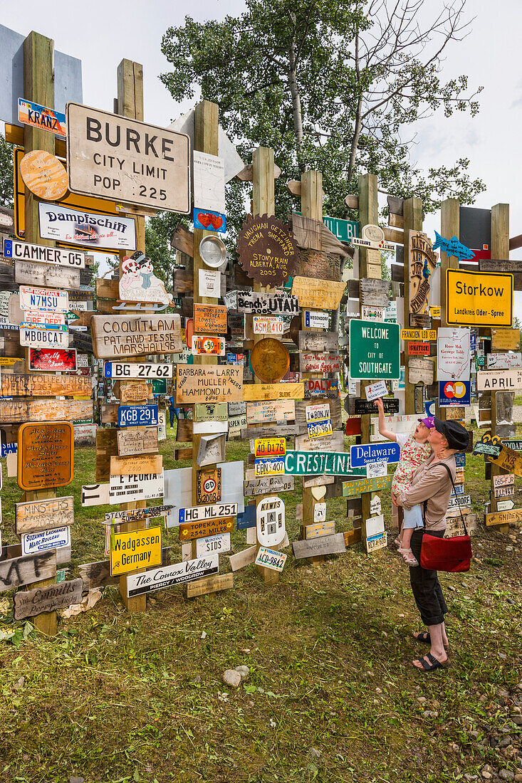 Mother and daughter explore the Signpost Forest, Watson Lake, Yukon Territory, Canada, summer