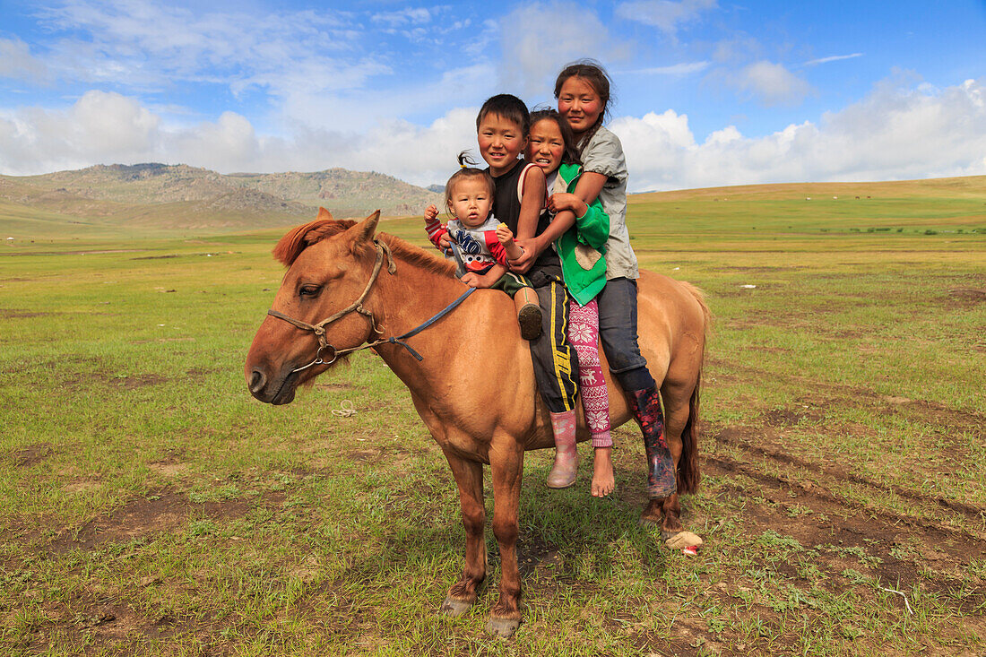 Four nomad siblings on their tame horse at summer nomad camp, Khujirt, Uvurkhangai, Central Mongolia, Central Asia, Asia