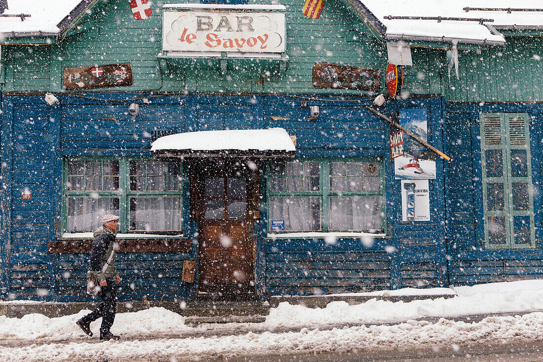 Mann bei Schneefall vor einer Bar, Argentiere, Frankreich