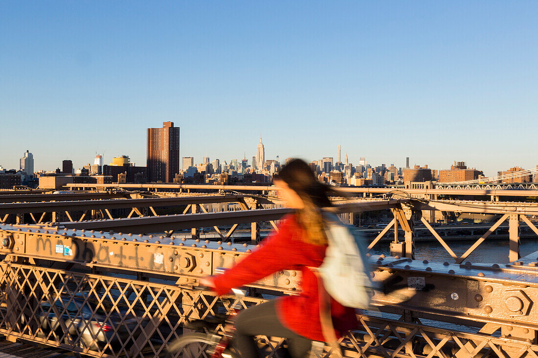 Fahrradfahrer, Frau, auf der Brooklyn Bridge, Blick auf Manhattan, Empire State Building, Skyline, New York City, USA, Amerika