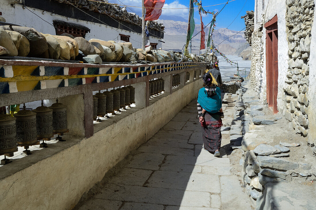 Junge Frau mit Baby an Gebetsmuehlen in Kagbeni, Ortschaft am Annapurna Circuit Trek mit buddhistischem Kloster im Kali Gandaki Tal, dem tiefsten Tal der Welt, Mustang, Nepal, Himalaya, Asien