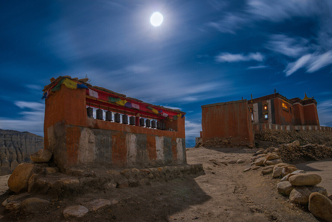Full moon above the monastery, gompa and prayer wheels in Tsarang, Charang, tibetian village with a buddhist Gompa at the Kali Gandaki valley, the deepest valley in the world, fertile fields are only possible in the high desert due to a elaborate irrigati
