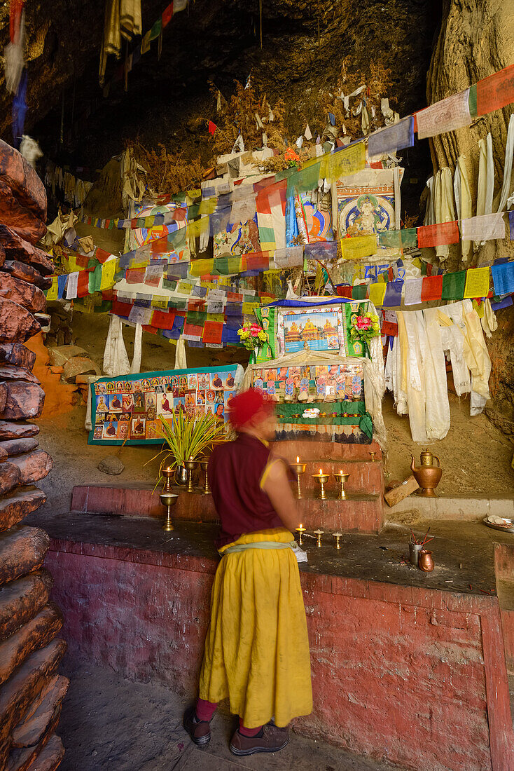 Moench am Altar der Ranchung Cave, buddhistisches Felsenkloster mit Gebetsfahnen, nahe Samar, Koenigreich Mustang, Nepal, Himalaya, Asien