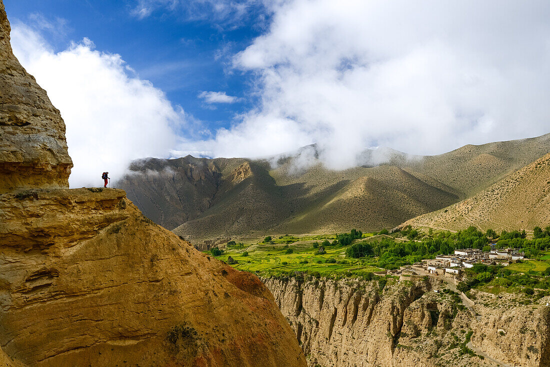 Young woman, hiker, trekker in the surreal landscape typical for Mustang in the high desert around the Kali Gandaki valley, the deepest valley in the world. Fertile fields are only possible in the high desert due to a elaborate irrigation system. In the b